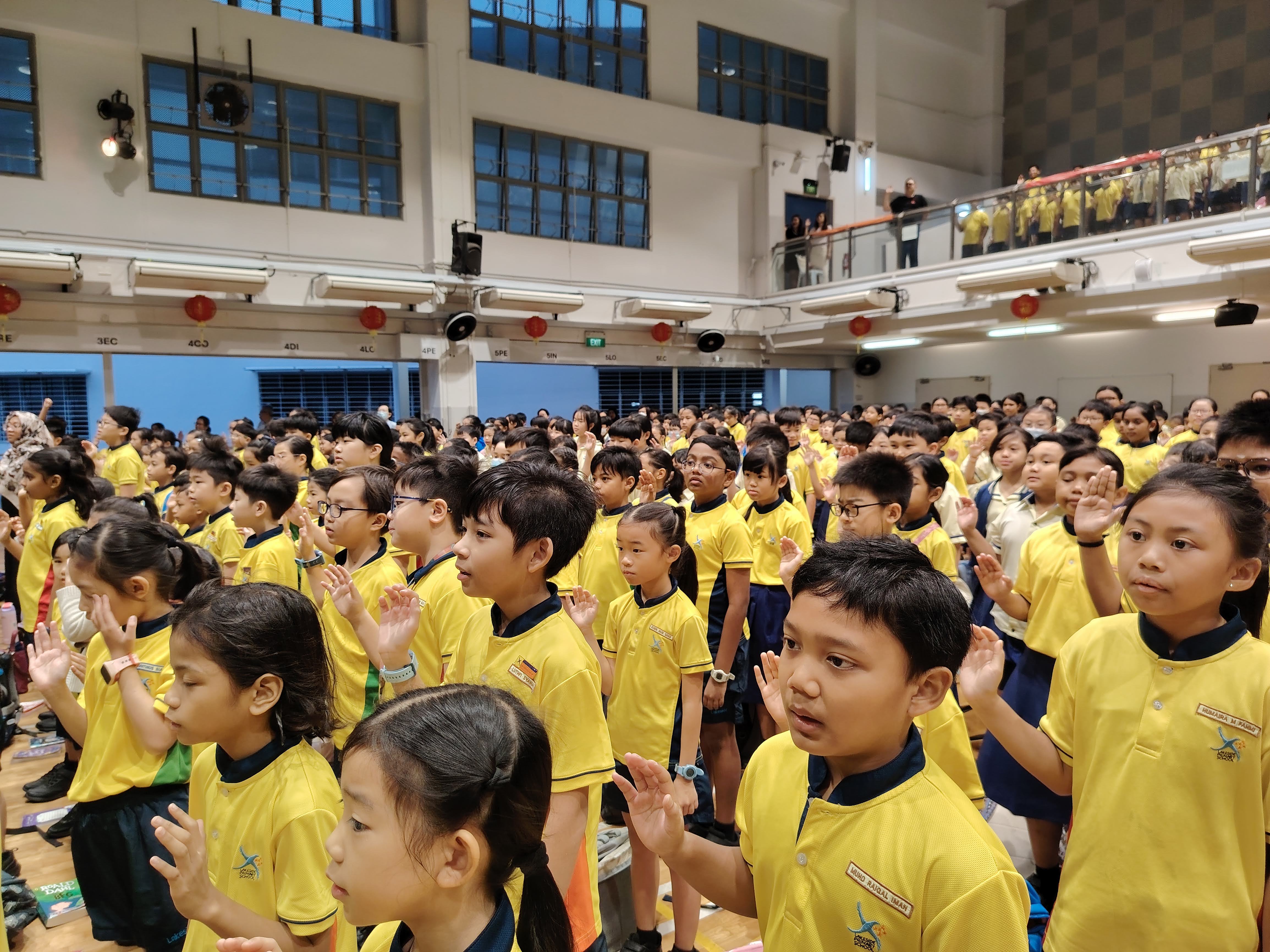 Students rising and raising their right hands and reciting the Spectators' Creed